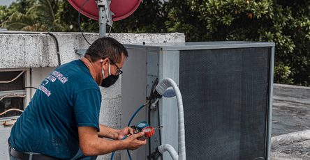 HVAC technician inspecting and servicing an outdoor air conditioning unit